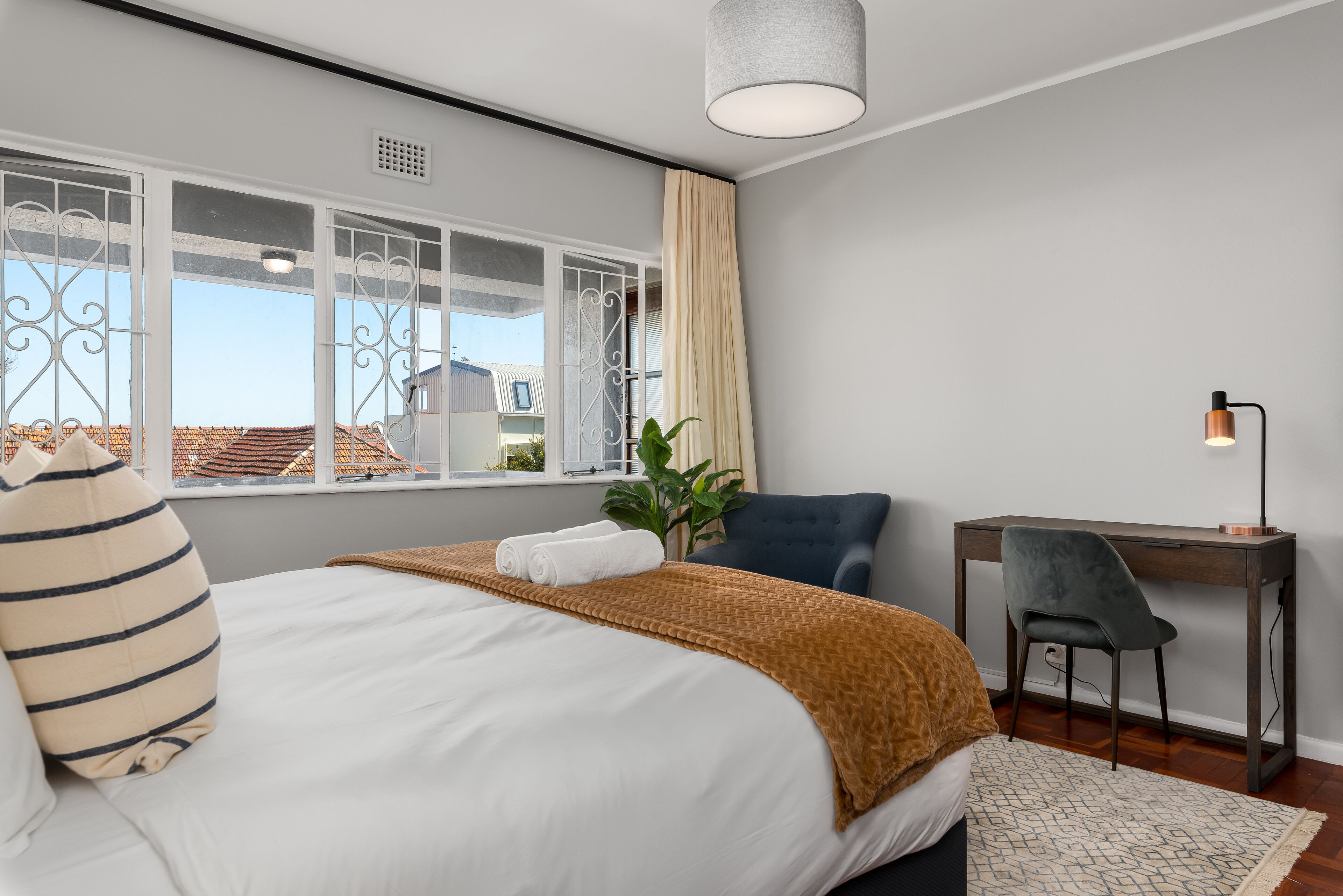Ein modernes Hotelzimmer mit einem großen Bett, einem Schreibtisch und Blick auf die Stadtlandschaft.