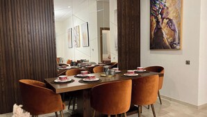 A dining area with a long wooden table set for a meal, surrounded by velvet chairs. - 2 Bed Apartment - Balcony, Parking, Wifi (Casablanca)
