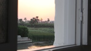 Vista a través de una ventana que muestra palmeras y un atardecer.