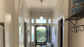 A hallway with a patterned rug, white walls, and a black door leading outside. - Florence Cottage, 10 minutes from Hunter Valley Vineyards. Family friendly.  (Cessnock)