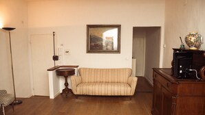 A living room with a sofa, a wooden cabinet, a framed painting, and a floor lamp.