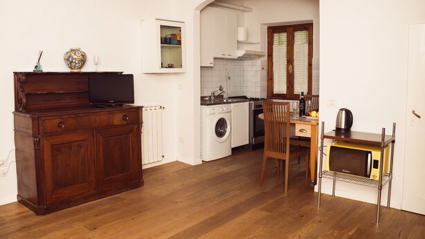 A compact kitchen with a washing machine, a microwave, and a wooden dining table.