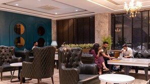 A modern lounge area with leather armchairs, a round table, and a potted plant. - Alpine hotel and villas (Dharamshala)