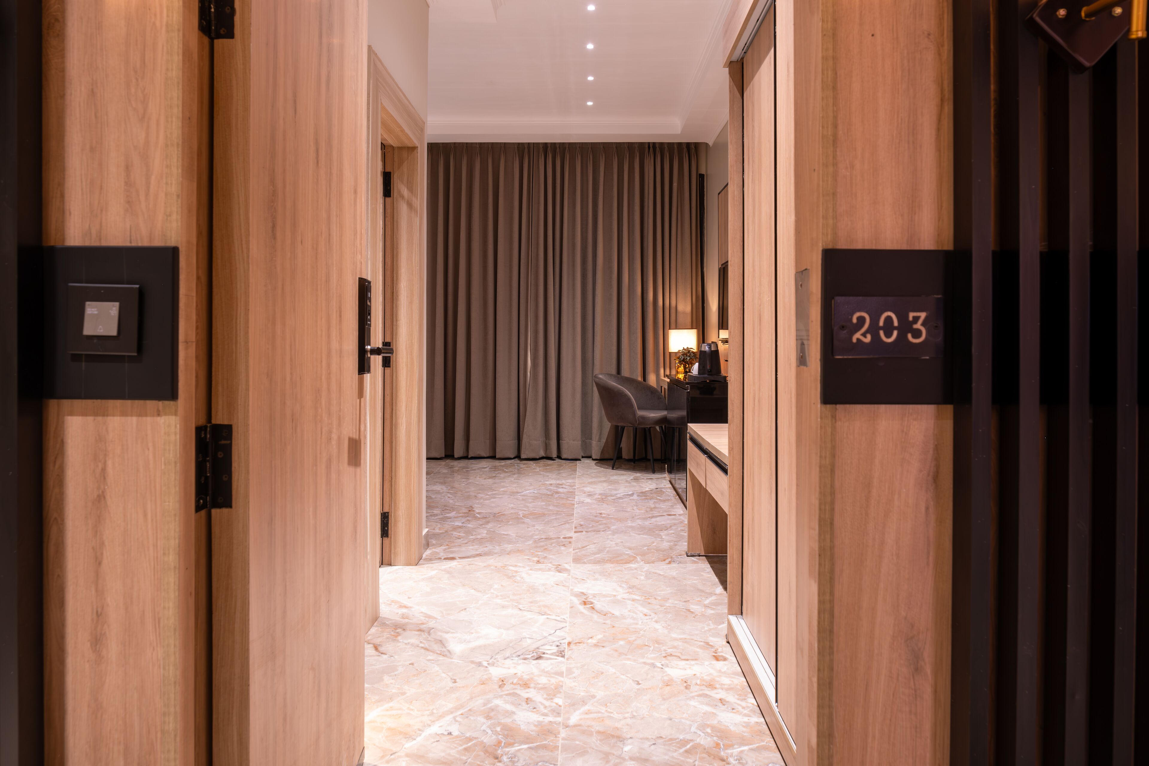 A hallway with wooden walls, a marble floor, a desk with a chair, and a curtain.