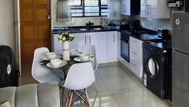 Cocina compacta con armarios blancos, horno empotrado y lavadora.