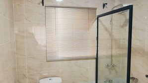 Un baño con inodoro, lavamanos y ducha con mampara de vidrio.