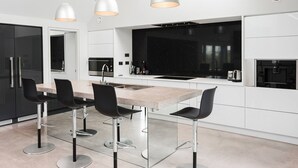 Una cocina moderna con una isla central, armarios negros y tres lámparas colgantes.