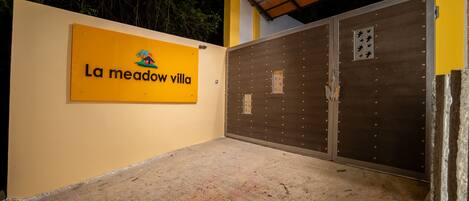 A yellow sign with "La meadow villa" and a closed metal gate.