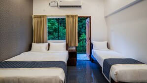Una habitación de hotel con dos camas, un ventilador de techo y una ventana con cortinas.