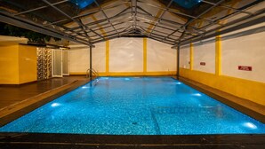 Una piscina interior con techo de cristal, agua cristalina y paredes amarillas.