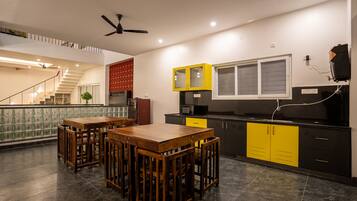 A modern kitchen with a dining area, featuring a staircase, a ceiling fan, and a kitchen island.