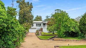 A two-story house with a front yard, a gravel driveway, and a well-maintained lawn.