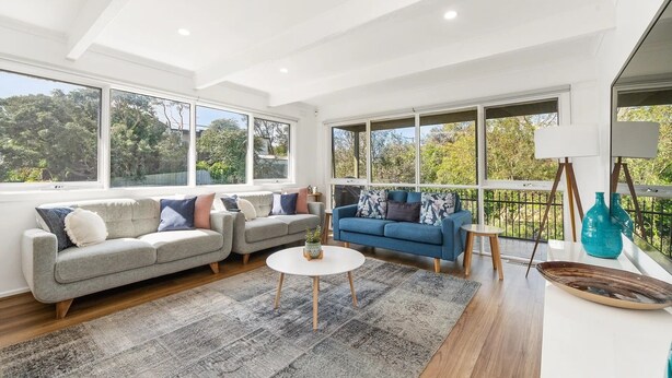 A spacious living room with a grey sofa, a blue sofa, and a white coffee table.