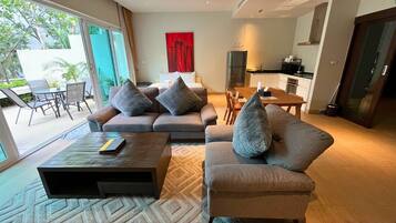 A modern living room with a sofa set, a coffee table, and a dining area with a kitchen in the background.