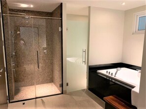 A modern bathroom with a glass-enclosed shower, a freestanding bathtub, and a minimalist sink area. - Olive 2 Beds Beachfront Condo Resort (Rawai)