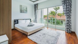 A bedroom with a large bed, a view of greenery and buildings outside, and a modern design. - Trixie Town House 2 With Private Pool (Rawai)