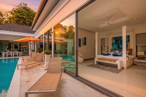A modern interior with a pool, lounge chairs, and a bedroom with a bed and artwork.