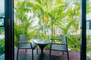 An outdoor seating area with wicker chairs and a glass table, surrounded by lush tropical plants. - Lotus Pool Villa Your Own Slice Of Island Paradise (Rawai)