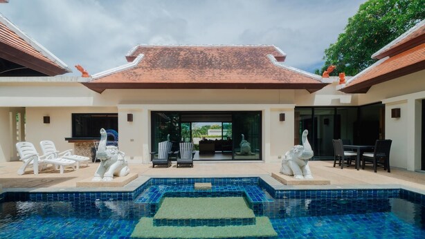 Une piscine dotée d’une terrasse carrelée, entourée de chaises longues et de statues.