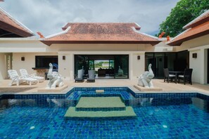 A swimming pool with a tiled deck, surrounded by lounge chairs and statues. - Lotus Pool Villa Your Own Slice Of Island Paradise (Rawai)
