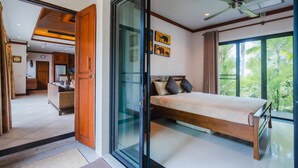 Une chambre à coucher avec un lit, un ventilateur de plafond et une vue sur la verdure environnante.