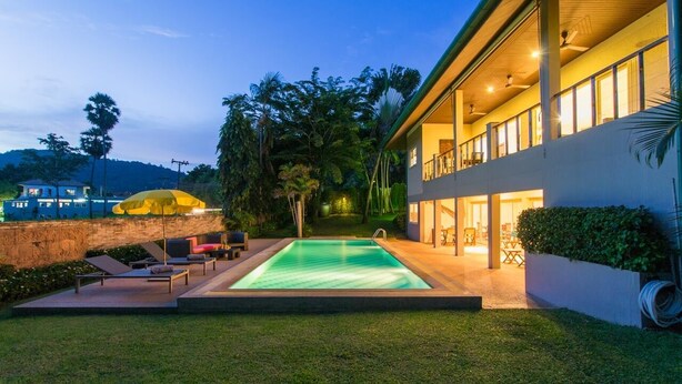 Une maison moderne dotée d’une piscine, d’un espace salon extérieur et d’un grand balcon.