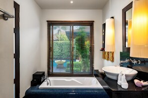 Un bagno moderno con una vasca da bagno ampia, un lavandino rotondo e una finestra con persiane.