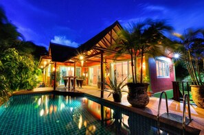 A poolside area with a pool, outdoor seating, and a building with large windows and doors.