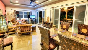 A spacious living area with a television, seating, and a ceiling fan.