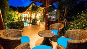 An outdoor seating area with wicker furniture and a pool in the background.