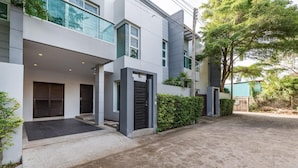 Une maison moderne à deux étages, dotée d’une allée couverte, de grandes fenêtres et d’un jardin bien entretenu.