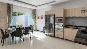 Une cuisine moderne équipée d’un four à micro-ondes, d’un réfrigérateur et d’une cuisinière intégrés. Un coin repas avec une table et des chaises est également disponible.