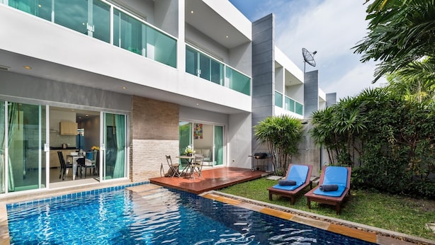 Un hôtel moderne doté d’une piscine, d’un espace extérieur aménagé et d’une végétation luxuriante.