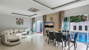 Un salon moderne comprenant un canapé, une table basse et un coin repas avec des chaises et un téléviseur.