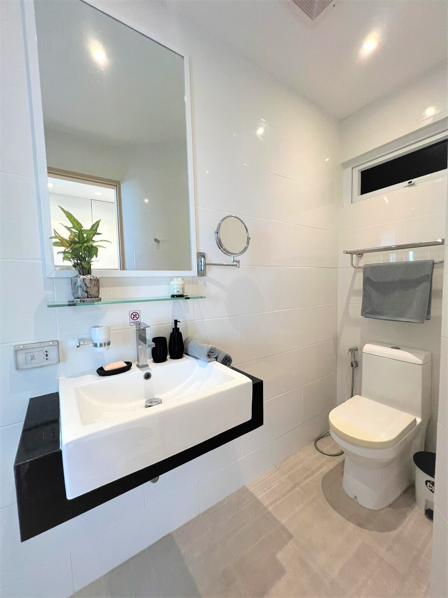 A modern bathroom with a white sink, mirror, and toilet.
