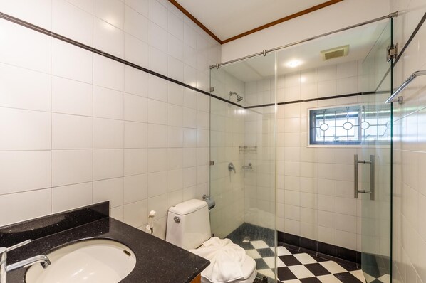 A modern bathroom with a glass-enclosed shower, a black and white checkered floor, and a white toilet.