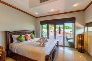 A hotel room with a large bed, a view of the outdoor balcony, and a sliding glass door leading to the balcony.