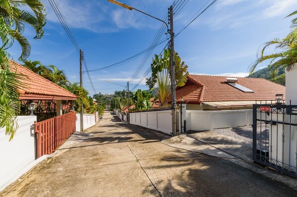 A narrow street lined with houses, a gated entrance, and a clear sky. - Aster Pool Villa, Your Tropical Villa In Paradise (Rawai)