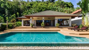 Une maison avec une piscine, entourée d’une végétation luxuriante.