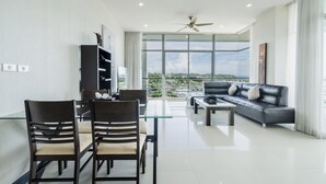A modern living room with a glass dining table, leather sofa, and a view of the cityscape.