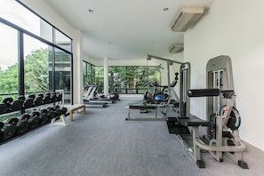 Un gimnasio moderno con equipo de cardio, mancuernas y una banca.