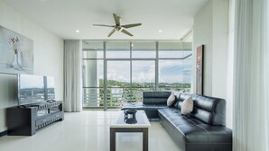 A modern living room with a sofa, a coffee table, a TV, and a ceiling fan.