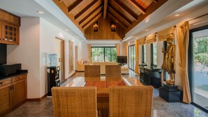 A spacious living area with a high ceiling, a large dining table, and a statue.
