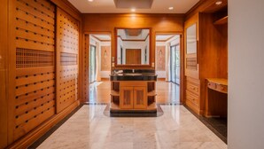A hallway with wooden paneling, a central black marble counter, and a wooden cabinet.