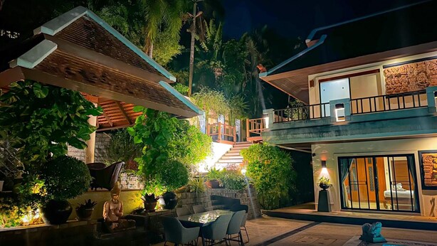 A two-story building with a balcony, outdoor seating area, and a swimming pool.