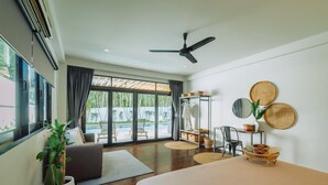 Une chambre d’hôtel moderne dotée d’un grand lit, d’un ventilateur de plafond, d’une vue sur une piscine et d’un balcon avec des meubles d’extérieur.