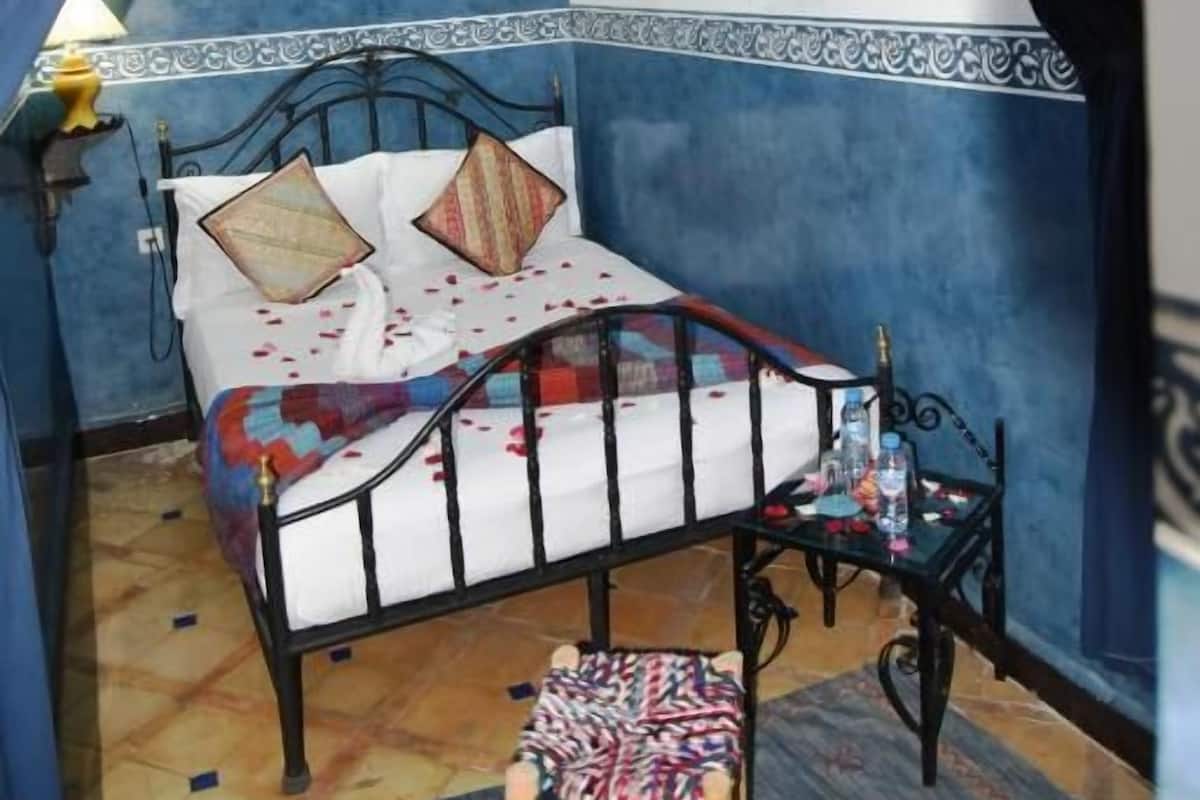 A room with a bed, a small table, and a chair.