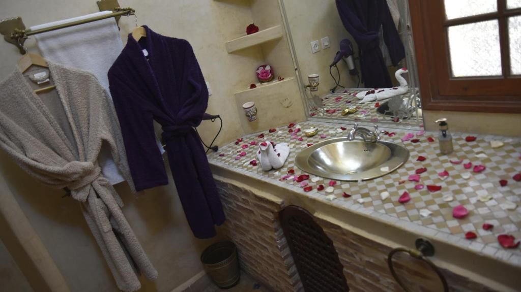 A bathroom with a sink, a mirror, and a towel rack with robes.