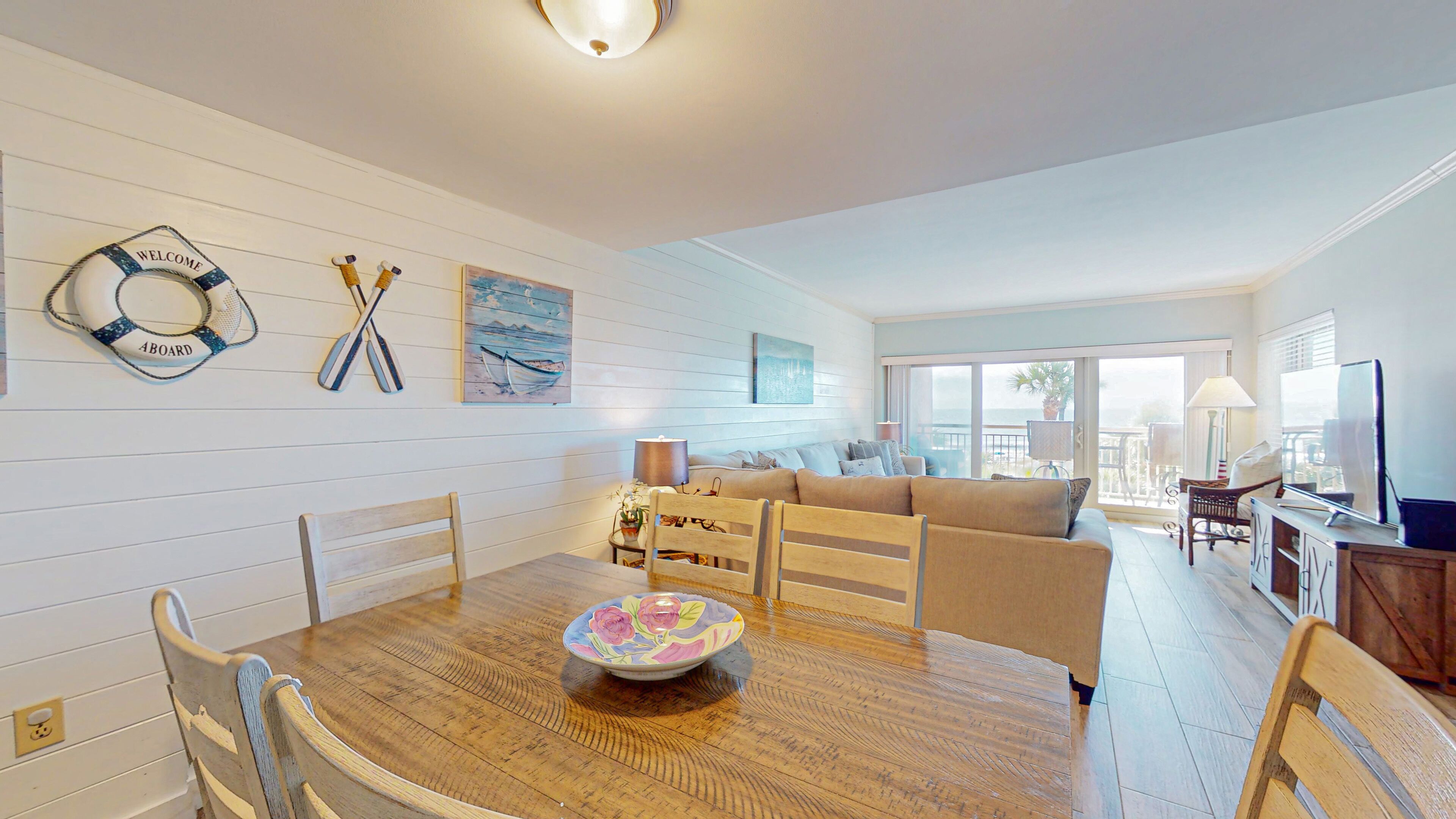 A spacious living area with a wooden dining table, a sofa, and a TV.