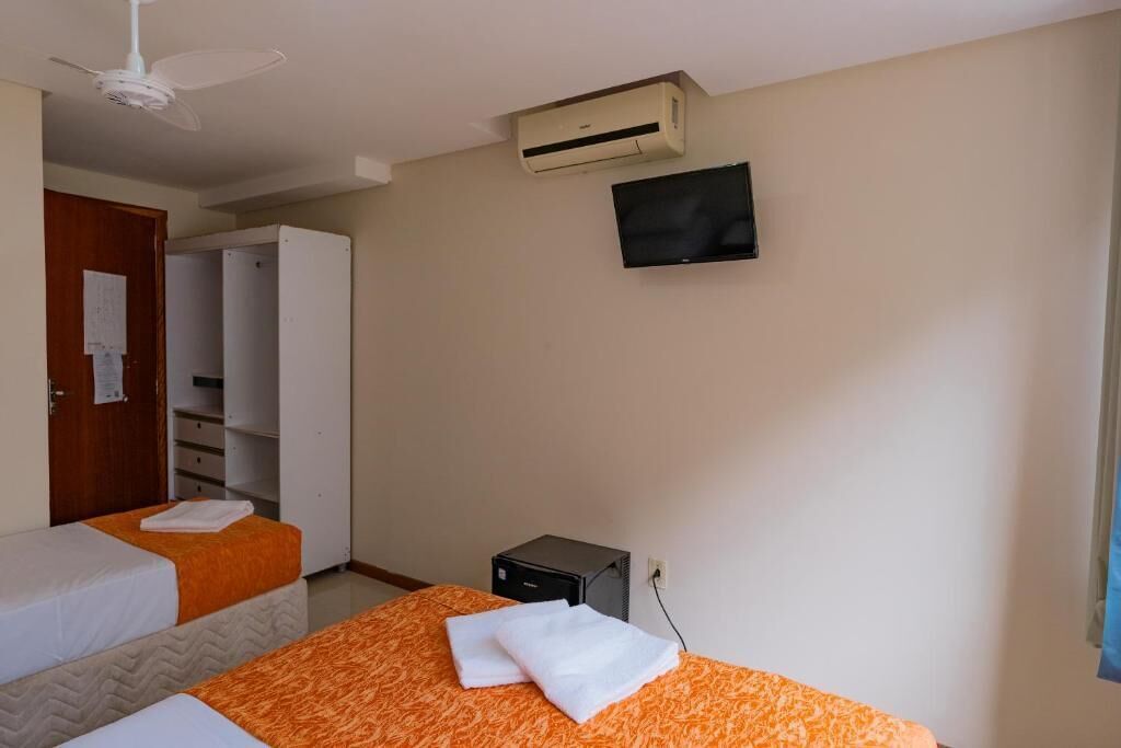 Une chambre d’hôtel avec deux lits, un appareil de climatisation, une télévision et un petit bureau avec un ordinateur.